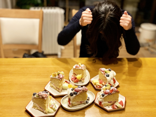 ケーキを前に頭を抱える女性
