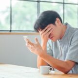 スマホを見て悩む人